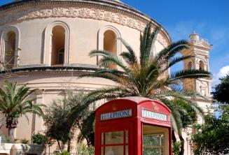 Een rode telefooncel in de voorkant van de Mosta Rotunda