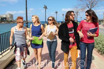 Studenten oefenen Engels na de les naast de St. Julians Bay, Malta