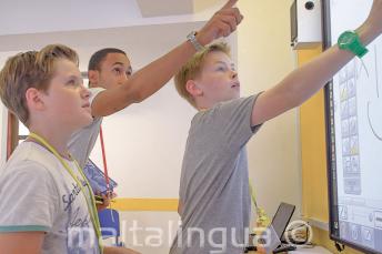 Leerkracht helpt studenten bij het interactief whiteboard