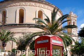 Een rode telefooncel in de voorkant van de Mosta Rotunda