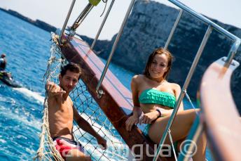 2 studenten loungen op het dek van een boot op Comino in Malta.