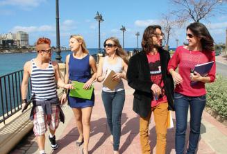 Studenten oefenen Engels na de les naast de St. Julians Bay, Malta