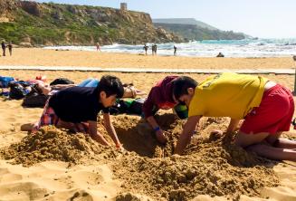 Groepsleider en studenten amuseren zich op het strand