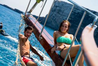 2 studenten loungen op het dek van een boot op Comino in Malta.