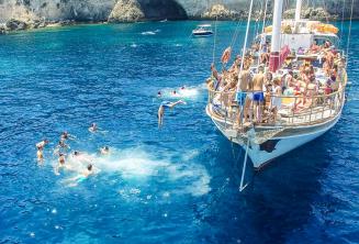 Taal studenten springen van een boot in Crystal Bay, Comino.