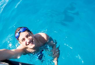 Een student zwemmen naast de boot op Comino.